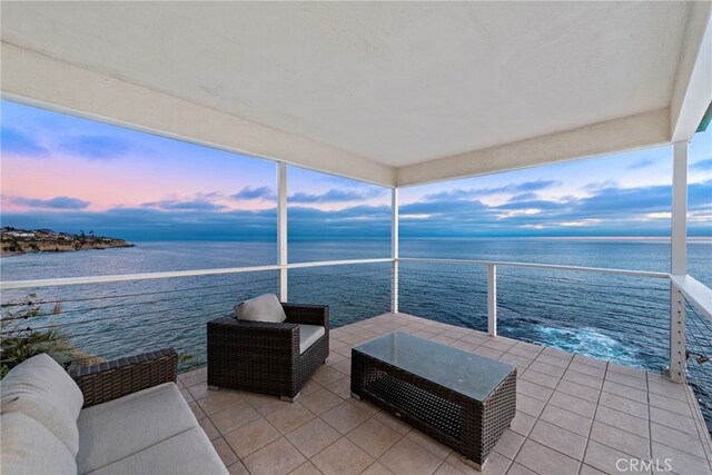 patio terrace at dusk with an outdoor hangout area, a balcony, and a water view