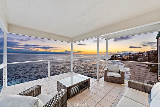 patio terrace at dusk with an outdoor living space and a water view