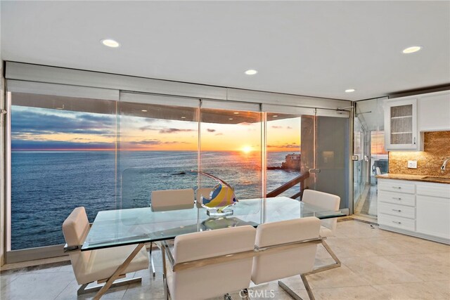 dining area with a water view, expansive windows, sink, and light tile patterned floors