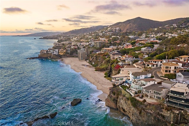 aerial view at dusk with a view of the beach and a water and mountain view