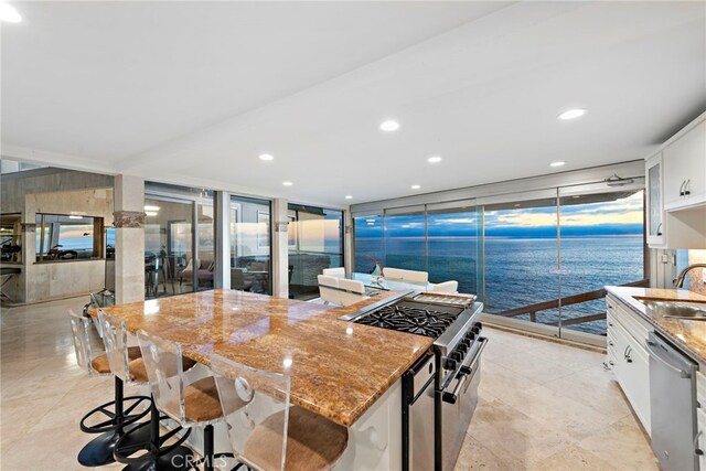 kitchen with white cabinetry, a water view, a center island, appliances with stainless steel finishes, and expansive windows