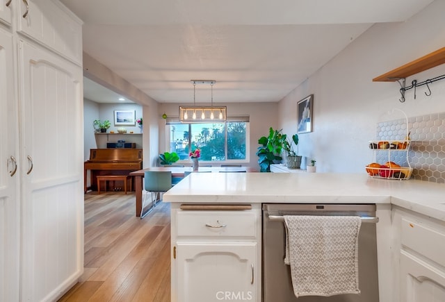 kitchen with kitchen peninsula, dishwasher, pendant lighting, and white cabinetry