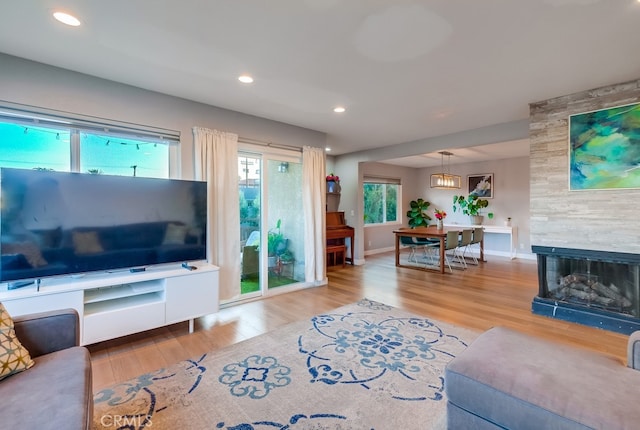 living room featuring wood-type flooring, a fireplace, and an inviting chandelier