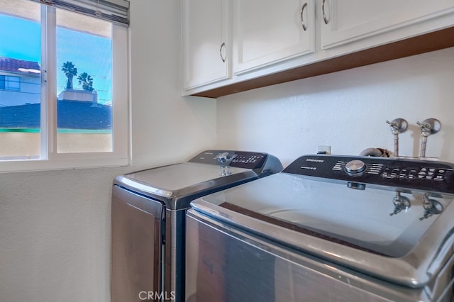 clothes washing area with cabinets, washing machine and clothes dryer, and a healthy amount of sunlight