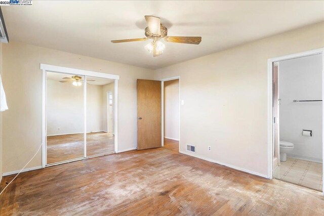 unfurnished bedroom with hardwood / wood-style flooring, ceiling fan, a closet, and connected bathroom