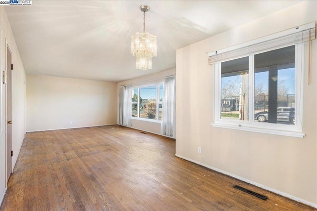 spare room featuring hardwood / wood-style floors and a chandelier