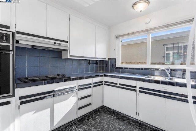 kitchen with black gas stovetop, tile countertops, white cabinetry, and backsplash