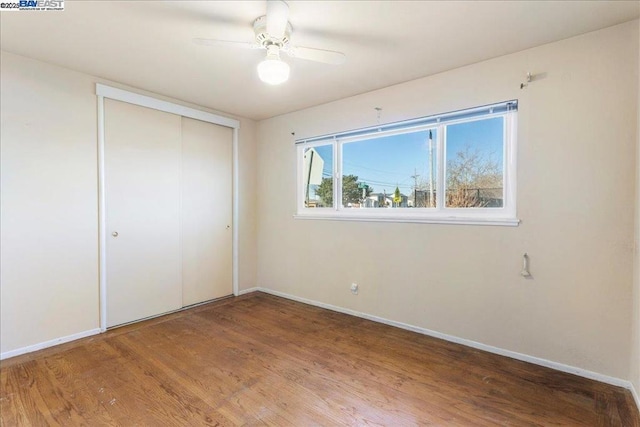 unfurnished bedroom featuring ceiling fan, a closet, and hardwood / wood-style floors