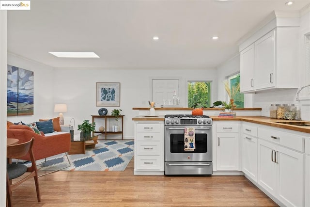 kitchen featuring white cabinetry, a skylight, butcher block counters, sink, and stainless steel range with gas cooktop