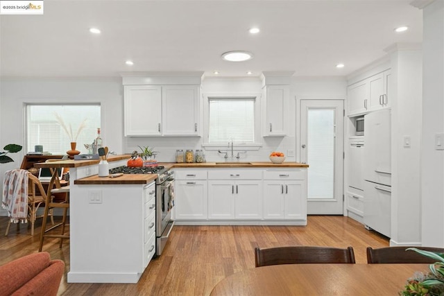 kitchen with white cabinets, wooden counters, and stainless steel gas range