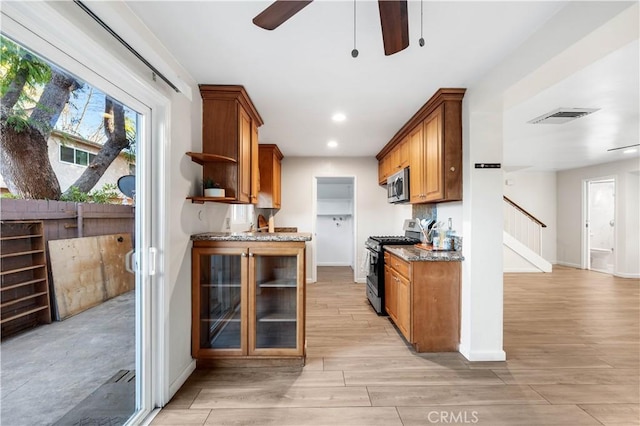 kitchen with light stone countertops, appliances with stainless steel finishes, and ceiling fan