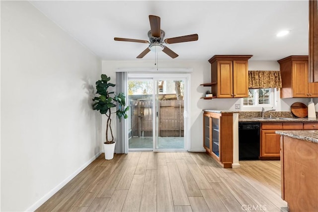 kitchen featuring sink, stone counters, black dishwasher, light wood-type flooring, and ceiling fan