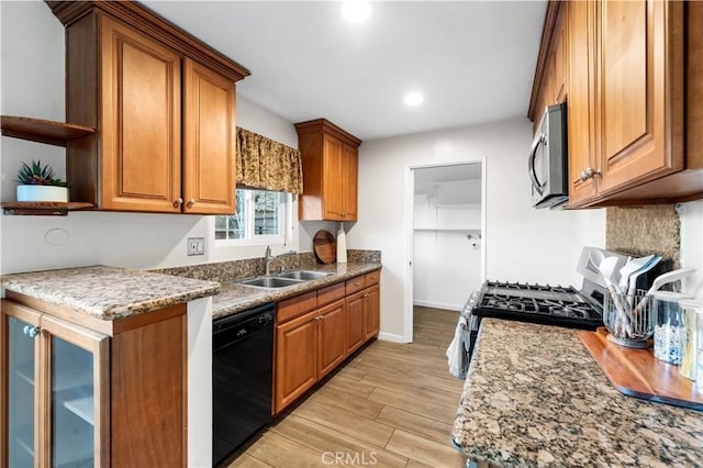 kitchen featuring sink, light stone countertops, black dishwasher, and light hardwood / wood-style flooring