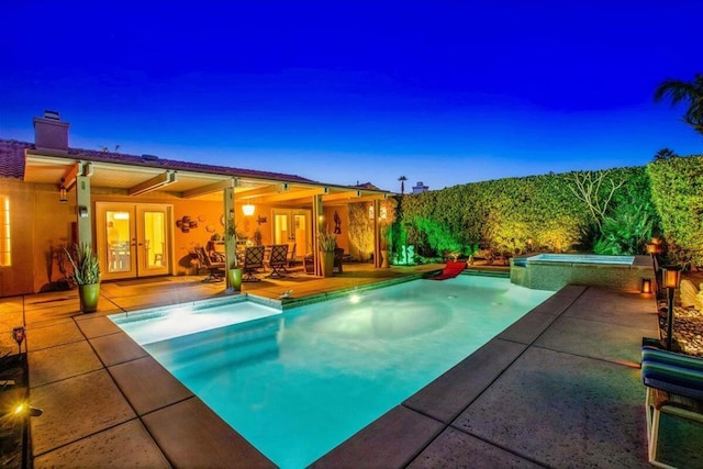 pool at dusk with french doors, an in ground hot tub, and a patio