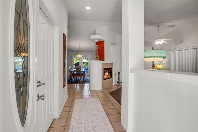 hall featuring light tile patterned floors and vaulted ceiling