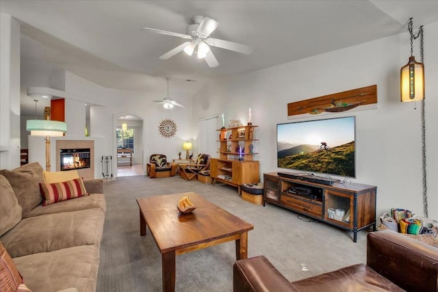 living room with a tiled fireplace, ceiling fan, and carpet flooring