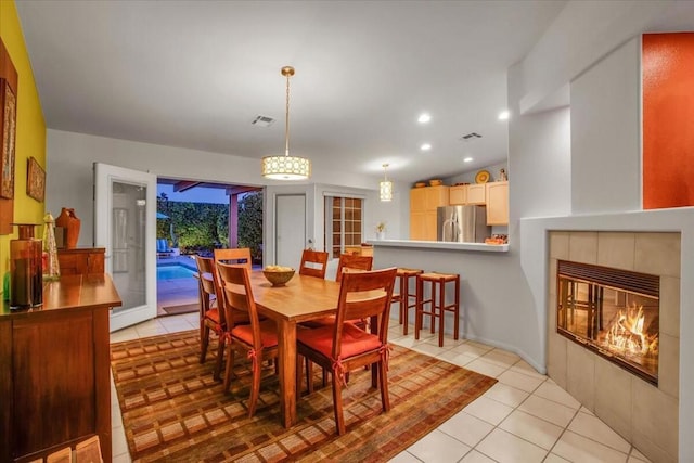 tiled dining area with a fireplace, french doors, and vaulted ceiling