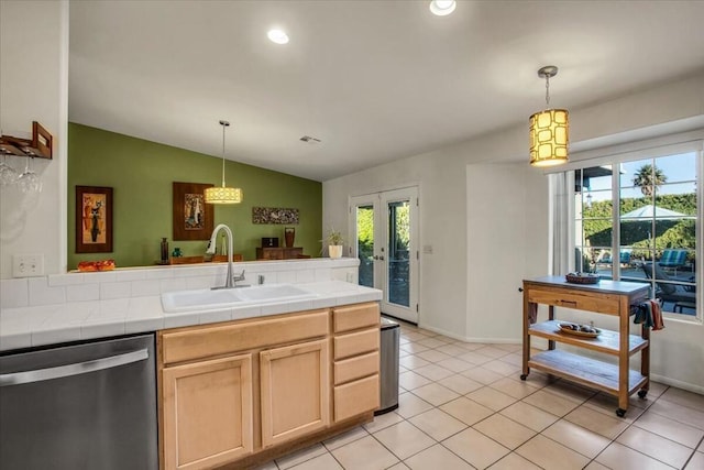 kitchen featuring sink, tile counters, a healthy amount of sunlight, vaulted ceiling, and stainless steel dishwasher