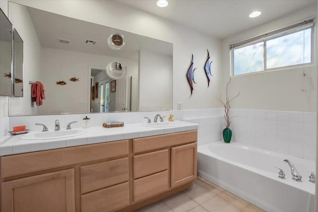 bathroom featuring vanity, a bath, and tile patterned floors