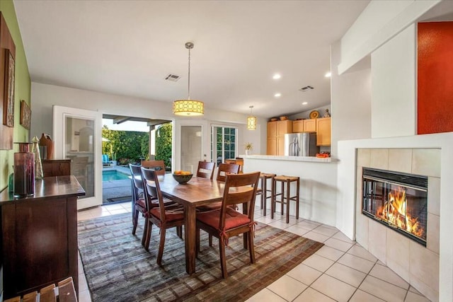 tiled dining room with lofted ceiling and a fireplace