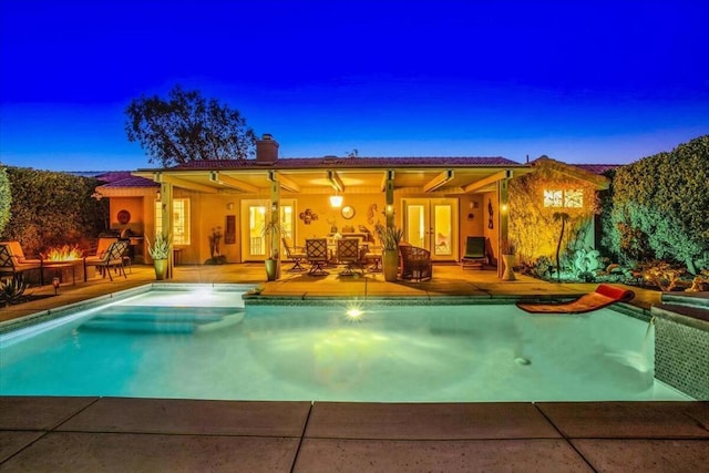 pool at dusk with a patio area, french doors, and an outdoor fire pit