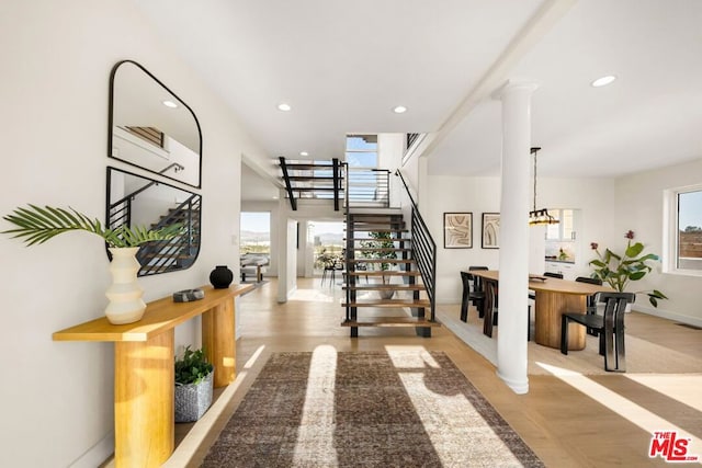 interior space with light hardwood / wood-style floors, a wealth of natural light, and decorative columns