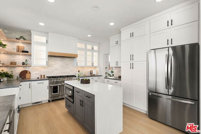 kitchen with light hardwood / wood-style flooring, stainless steel appliances, white cabinetry, and tasteful backsplash