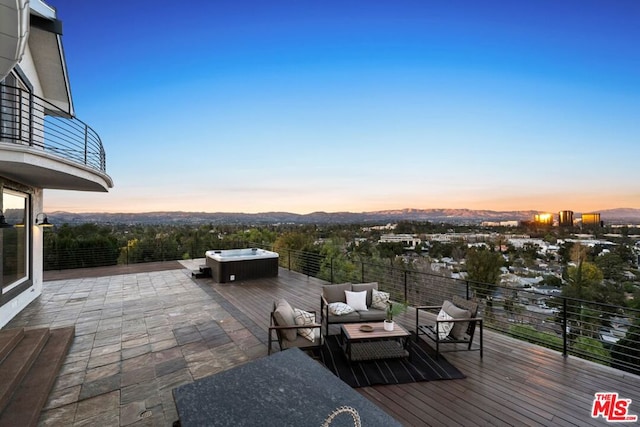 deck at dusk with a hot tub, an outdoor hangout area, and a patio