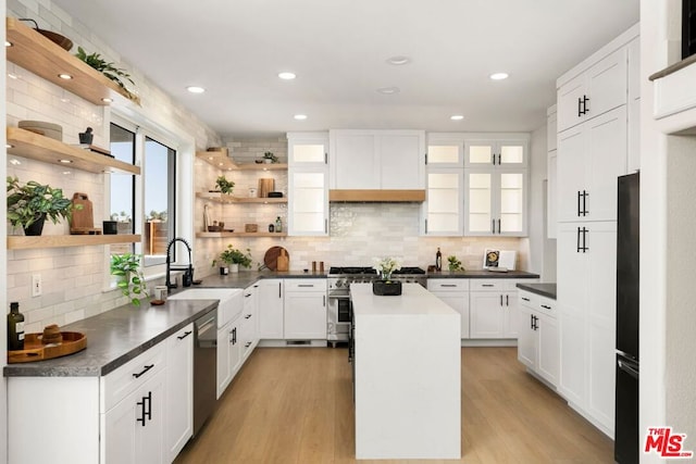 kitchen featuring sink, white cabinets, tasteful backsplash, a kitchen island, and appliances with stainless steel finishes