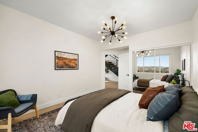 bedroom with hardwood / wood-style floors and an inviting chandelier