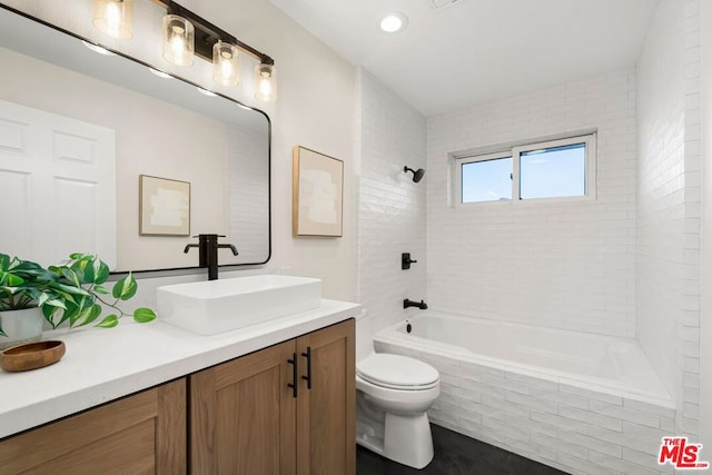 full bathroom with tiled shower / bath, vanity, and toilet