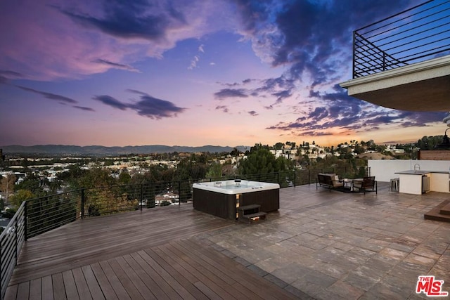 deck at dusk featuring a patio, a hot tub, an outdoor hangout area, and a mountain view