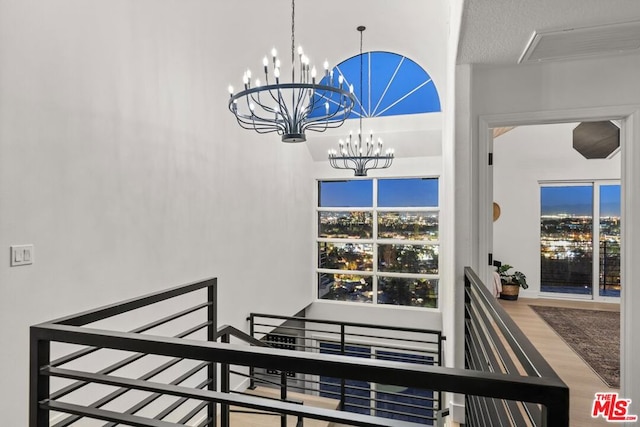 staircase with a textured ceiling, an inviting chandelier, and wood-type flooring