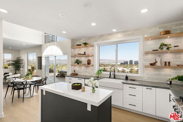 kitchen with a kitchen island, white cabinets, a wealth of natural light, and sink