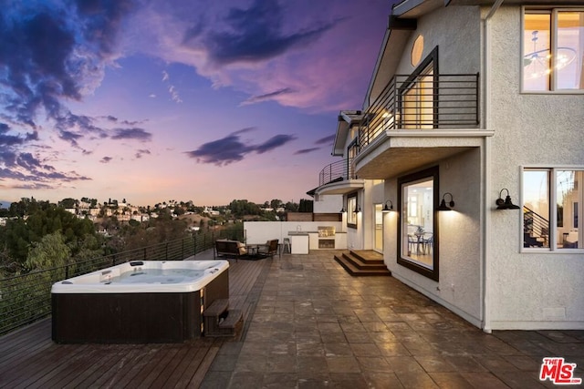 patio terrace at dusk with a hot tub and a balcony