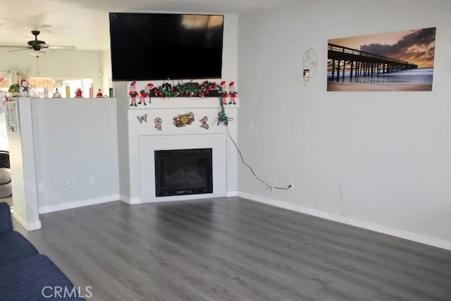 unfurnished living room featuring ceiling fan and dark wood-type flooring