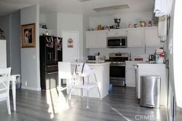 kitchen featuring wood-type flooring, white cabinets, stainless steel appliances, and a kitchen island