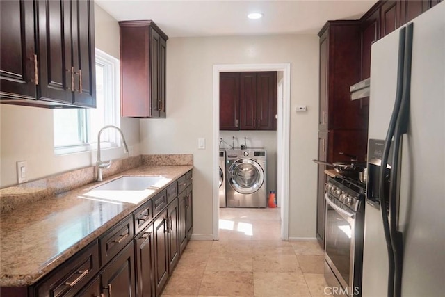 kitchen featuring sink, light stone counters, oven, refrigerator with ice dispenser, and washer and clothes dryer