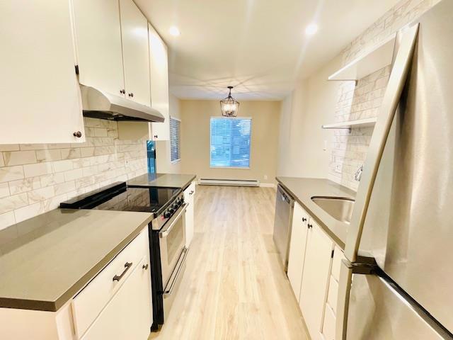 kitchen with a chandelier, appliances with stainless steel finishes, pendant lighting, a baseboard heating unit, and white cabinetry