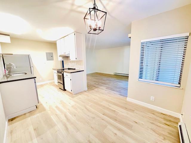 kitchen featuring stainless steel electric range oven, a baseboard heating unit, white cabinets, backsplash, and sink