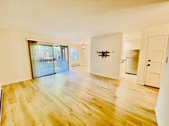 empty room with light wood-type flooring and a baseboard radiator