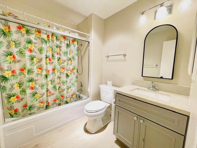 full bathroom with toilet, shower / bathtub combination with curtain, and vanity