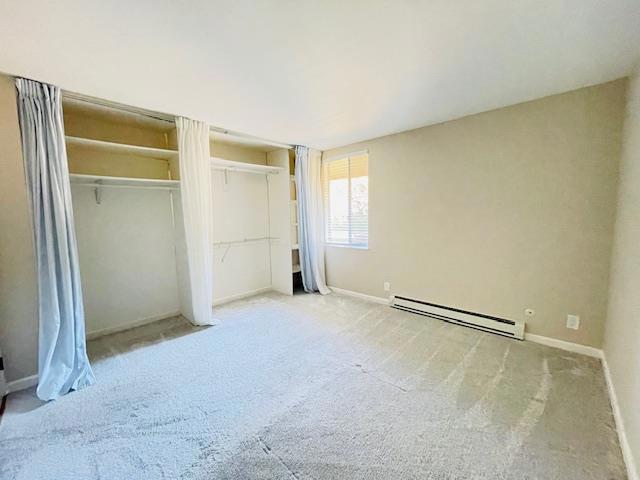 unfurnished bedroom featuring baseboard heating and light colored carpet