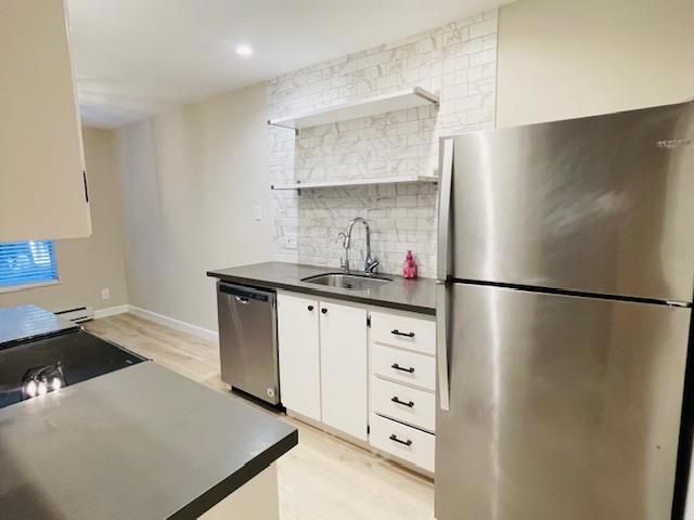 kitchen featuring a baseboard heating unit, light wood-type flooring, white cabinets, appliances with stainless steel finishes, and sink