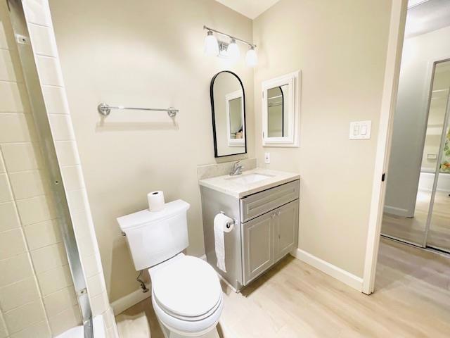 bathroom with toilet, wood-type flooring, and vanity