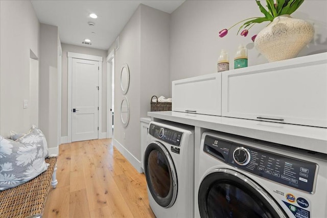 laundry room with separate washer and dryer, cabinets, and light hardwood / wood-style flooring