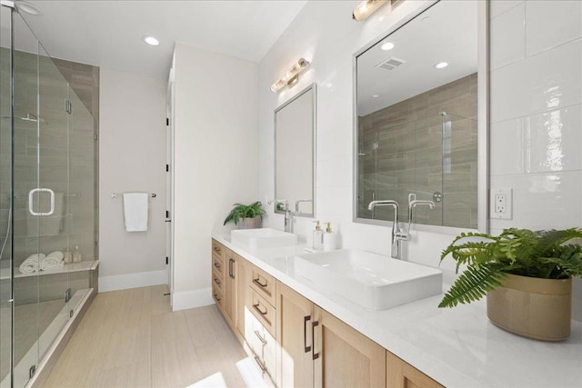 bathroom with a shower with door, tile patterned floors, and vanity