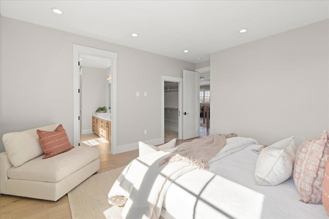 bedroom with ensuite bathroom, light wood-type flooring, a walk in closet, and a closet