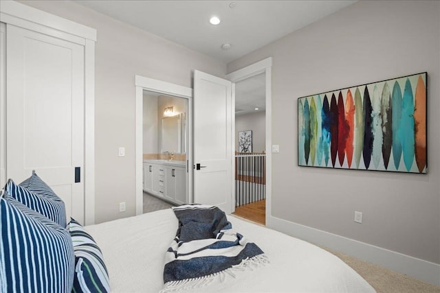 bedroom with sink, ensuite bath, and carpet floors