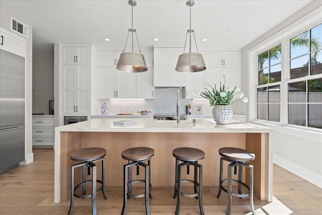 kitchen with stainless steel appliances, a kitchen island with sink, and white cabinetry